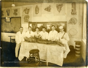 Students pose around the examination table with a cadaver. None of the subjects are identified including the cadaver.
