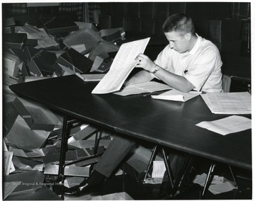 'Unidentified student surrounded by cap and gown boxes'