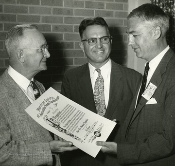 'P.I. Reed , Chairman of the ASJSA Committee on Awards; Quintus C. Wilson, president of ASJSA and chairman of the department of journalism, University of Utah, Salt Lake City; Kenneth MacDonald, editor of the Des Moines Register and Tribune and, in 1955, president of the American Society of Newspaper Editors. Mr. MacDonald is receiving the 1955 ASJSA Scroll for his newspapers because they were voted as especially distinguished in leading and shaping the economic, social, and cultural life of the area in which they circulate. The presentation took place August 23, 1955, at the University of Colorado, Boulder.'