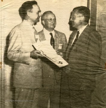 'Receives Newspaper Award--James Russell Wiggins (right), vice-president and managing editor of the Washington Post and Times-Herald, is shown receiving the ninth annual citation of the Association for Education in Journalism in behalf of the newspaper. The presentation was by Professor J. Douglas Perry of Temple University. Dr. P.I. Reed of the University of West Virginia is in the center. The association`s annual meeting is under way here.'