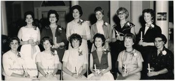'U' Dames Club officers, for the 1963-1964 school year, posed and holding candles.