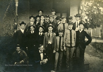 'The Beanery' at WVU poses on a front porch. Identified are: Charles Alexander Ellison, second row, second from right in uniform; Addison Dunlap Ellison, third row front right, in uniform, hand on his brother's shoulder.'