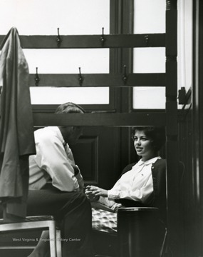 View of Sharon Luchsenger talking behind a man behind a coat rack.