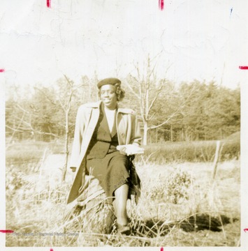 Portrait of African-American student, Mary Dodson, seated on a tree stump.