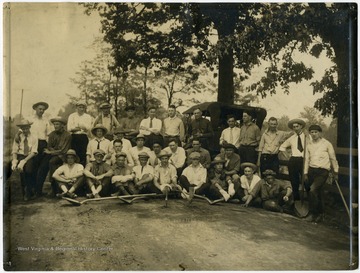 'Students from West Virginia University who dropped their books for 2 days to work on a mile stretch of bad road in Monongalia County in connection with the Good Roads Movement. 1)Seated on ground- Roscoe Posten, C. P. 'Mike' Leatherwood, Mos Darst, Unknown, Williams, Unknown, Teter, 'Rabbit' Rahl, Fred Chenoweth. 2)Seated - Bob Hogg, Four Unknowns, Billekim Smith, Jack Hagan, Unknown, Stu Race (unsure), Unknown.3)Standing- next to last Lefty Barron, Rest Unknown.'