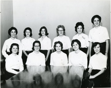 Members of Associated Women Students Judicial Board pose for a group portrait; they are dressed alike with white top and dark bottom.