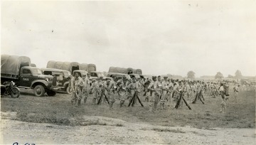 WVU R.O.T.C. cadets in formation at Summer Camp.  A row of military tracks and vehicles are shown in the background.