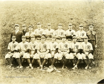 A group photo of baseball squad in uniform with a coach and a few other members.