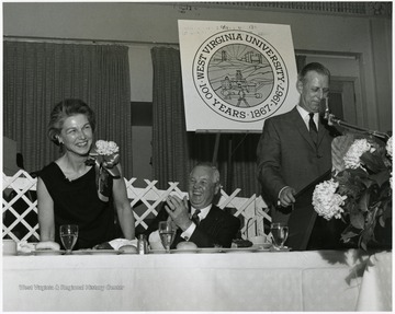 At the WVU's 100th Anniversary Birthday dinner, from left to right: Mrs. Thomas White, Governor Smith, and Mr. Thomas White are seated at the head table.