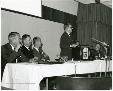 'Peter Muirhead, associate U.S. commissioner of education, is shown speaking at the Sept. 12, 1967 seminar on "The State University."  Also shown, from left to right, are: Keith Glancey, WVU prof. of education; Thomas Isaack, WVU prof. of management; Thomas Canning, WVU prof. of music; Ruel Foster, WVU prof. and chairman of English and chairman of the seminar planning committee; and James G. Harlow, president of WVU.'