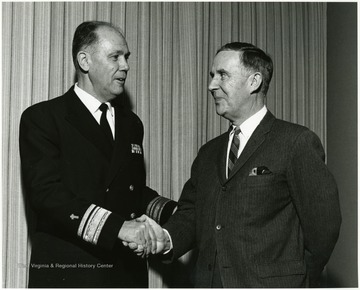 'Read Adm. James W. Kelly, chief of Naval Chaplains (left), shakes hands with Rev. Joe Gluck, WVU director of Student Affairs at "Man and His Religions" Symposium Jan. 7-9, 1968.'