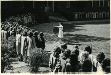 Sorority student who gathered around the Woodburn Circle sings at a direction of  Voncele Farr of Morgantown.