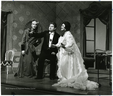 Man in a tuxedo with a man and a women in night clothes.