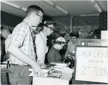 Students, including freshmen wearing beanies, in line to pay for their books. 'Right to Left, Chuck Trader and Charlotte Sneddon.'