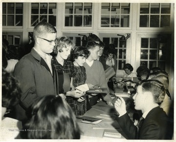 Possibly freshmen registration day. Male student with glasses standing is Trubie Turner.