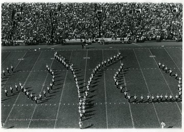 WVU Marching band in formation to spell 'WVU' on the field.