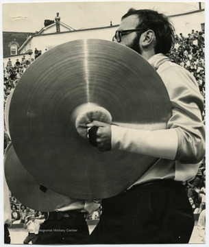 A cymbalist performs with the band on the field.