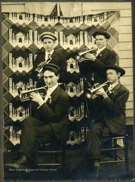 Group portrait of cornet band members holding their instruments.  Written on the back, 'The fellow standing on the right is Mr. L. H. Row; standing on the left is Mr. Bob Moore; sitting on the right is Oscar Harris; sitting on the left is Mr. W. A. Knapp. The one standing on the right opposite is the Leader of the Band here, Mr. Row.  Yours Truly, W. A Knapp, Junior, W. Va.'