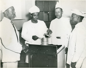 Four male students with a pot on a stove.