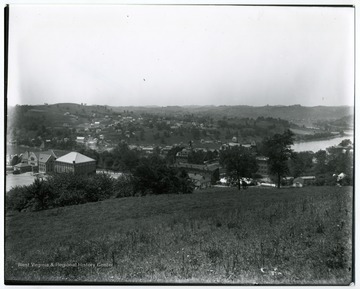 A view of campus, from left to right Library (present Stewart Hall), Commencement Hall, Agricultural Experiment Station, Martin Hall, Woodburn Hall and Science Hall (present Chitwood Hall) and hills of Westover spread beyond the Monongahela River in the distance.