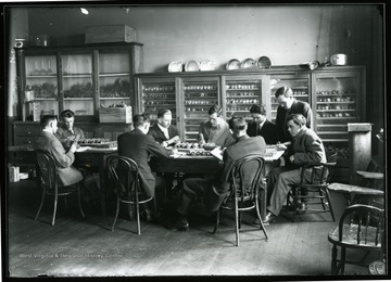 Students seated around a table examining ears of corn.