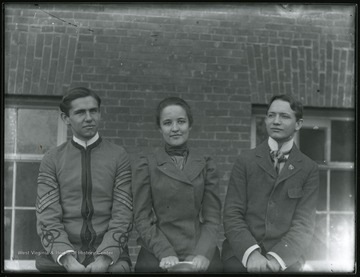 A female student sitting between male students: a male student on the left wearing cadet uniform.