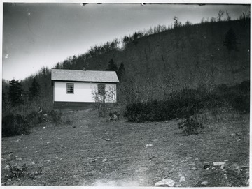 A view of Durbin School house on a hill; there is a person to the left of the building.