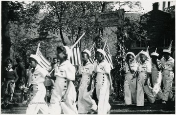 Eight Black girls carry flags in a parade. 