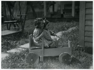 Two girls play in a home-made wooden children's car.