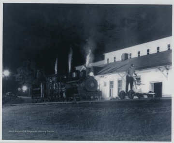 'Black and white print of Cass Scenic Shay #11 is posing along with Bret Evanich who is standing on the Collis P. Huntington Chapter, National Railway Historical Society of Huntington, WV's handcar. Photo by Herbert Parsons.'