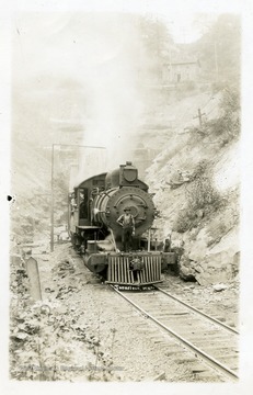 A locomotive engine passing Tunnelton, West Virginia; a man is standing over the grill of the engine.