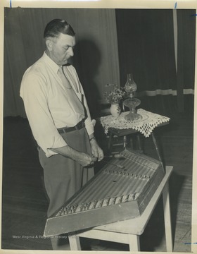 'Keith Simmons performing an old song variously titled 'The Devil's Quickstep,' and 'Old Aunt Jenny with the Nightcap On.' The instrument, a true dulcimer, is a family heirloom which was damaged during a Civil War skirmish. Simmons plays it with two mallets made of wool yarn wrapped on corset staies.'