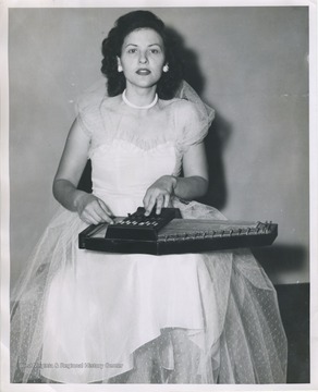 'Mary Belle Workman singing songs taught to her by her mother; playing an autoharp.'