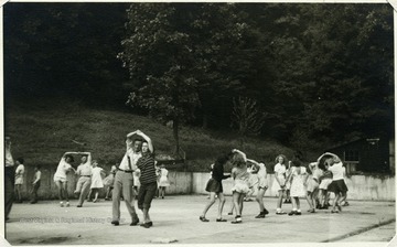 'A class in Folk games as taught by Betty Smith, older club girl, and Werner Wegman, camp director.'