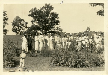 Group of women standing near garden plantings.