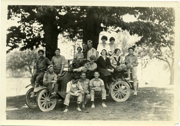 4-H members pose around an automobile: J. Burton, C. Shaffer and Adele B. are in photo.