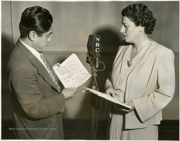 'Jen Ying Yen, Chinese journalist, reads his part in the script "America Speaks to China" as Pearl Buck, author of the play, looks on.  These NBC dramas, eight in all, are sponsored by the East and West Association and will be short waved to China.'