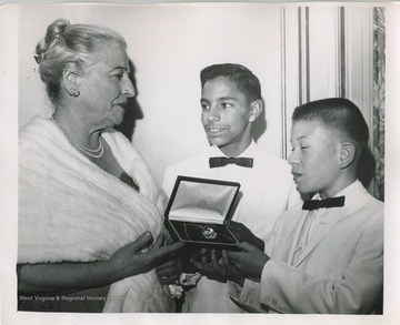 'Left to right, David and Leon Yoder the first two children taken into the Welcome House family in 1949 present a locket of friendship to Nobel prize winner Pearl S. Buck, chairman of the Board of Welcome House...'