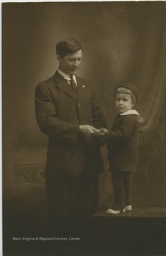 A portrait taken of a young child holding hands with his father. 
