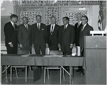 Gov. Smith (center) with a group of men standing around a conference table.
