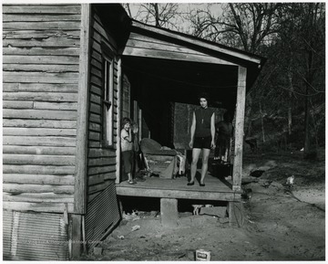 Two women and two children standing outside on the porch of a house.