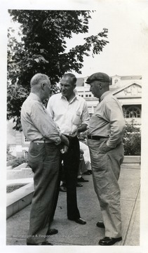 Photo from WVU College of Mineral Resources Scrapbook. Three unidentified men standing outside Clark Hall, WVU.