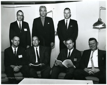 A group portrait of West Virginia University faculty including Jerry Burchinal (seated, far right), Civil Engineering, Dr. Stocks (standing, far right), Economics, Thomas W. Gavett (standing, middle), and David Little (seated, far left), Geography.