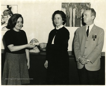 Dr. Clarkson (far right) standing in front of artwork with two female students.