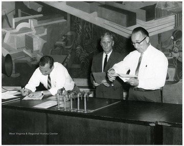 A photograph of President Paul Miller (center) with C.E. Silling (right), chief architect for original Medical School building, and another man inside a room in White Hall.