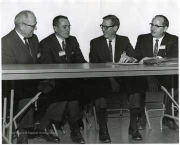 A group portrait of four men sitting at a table.