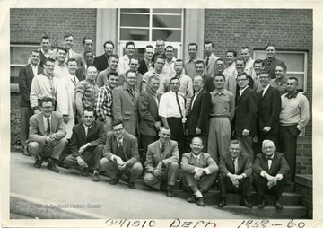 A group portrait of the graduate students and instructors of the WVU Physics Department.  The graduate students are standing and the instructors are kneeling.   Instructors (left to right) are: Gerald Arthur, Michael Pavlovic, Arnold Levine, Douglas Williamson, Harvey Rexrode, Charles Thomas, Dr. Ford.