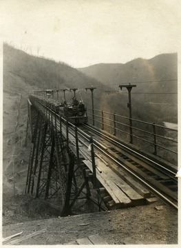 A photograph of an open car coal mine train crossing a bridge.