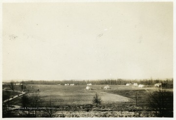 A photograph of an open field with a small number of homes included.