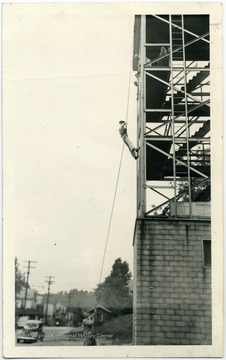One man holding the rope as the other scales the building.